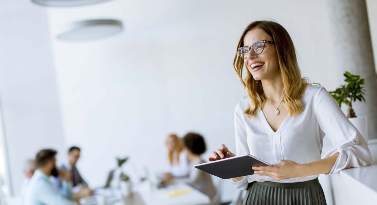 smiling woman holding a tablet in a meeting